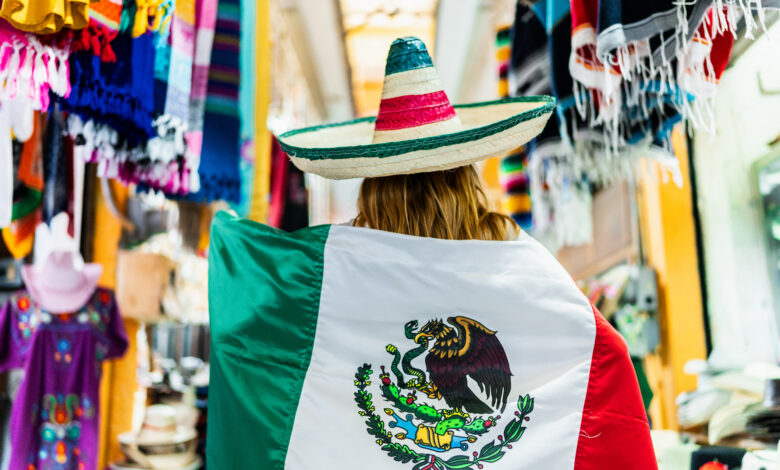 Young woman walking and holding a mexican flag at street market