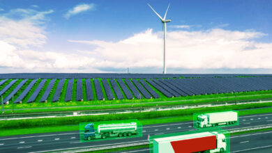 Green cargo trucks driving in a sustainable environment surrounded by solar and wind energy.