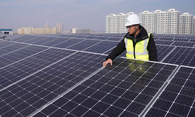 A Chinese worker inspects rows of solar panels at a photovoltaic power station on the rooftop of a plant building in Zouping, Binzhou City, east China