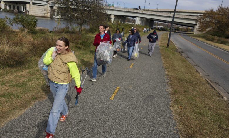 Volunteers carry bags of trash collected along the river trail to a sorting site on Wednesday, Nov. 15, 2023, at Anacostia Park in Washington
