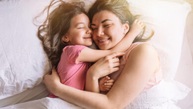 Daughter and mother lying in bed hugging and smiling