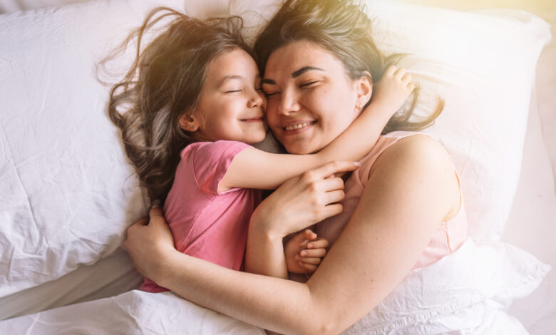 Daughter and mother lying in bed hugging and smiling