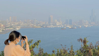 Woman takes a picture of Kaohsiung’s skyline, which is obscured by smog
